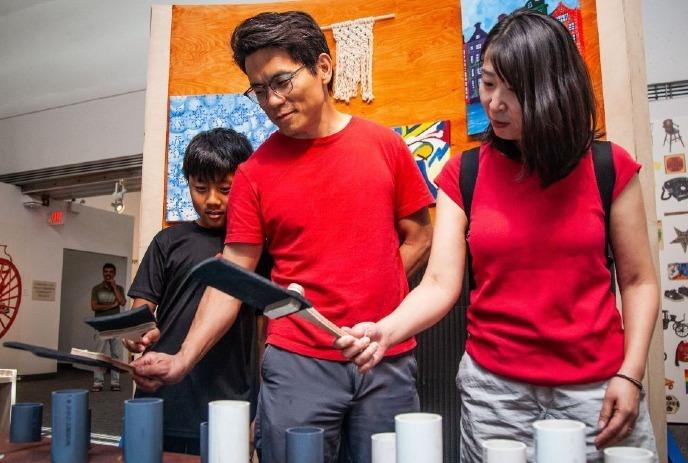 Three people in red shirts collaboratively looking at cups on a table in a colorful room.