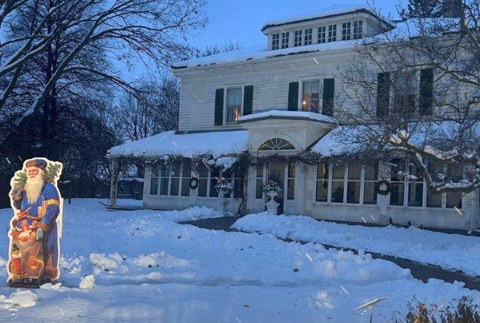 Eldon house at twilight, Santa's here with gifts, lights glowing, festive warmth all around.