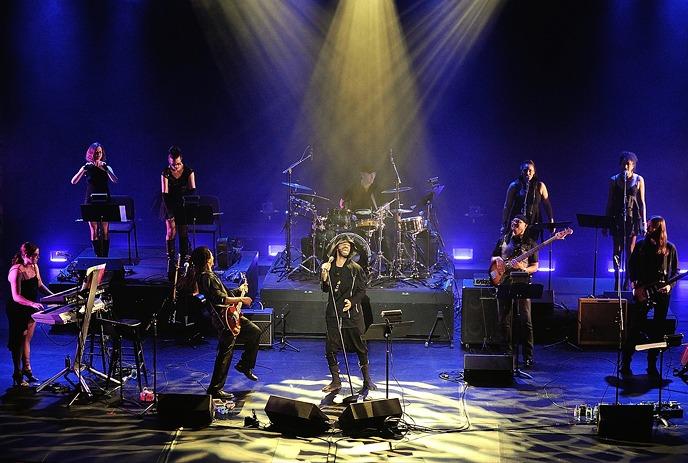 Classic Albums Live band performs on stage with the lead singer in a black hat under colorful lights.