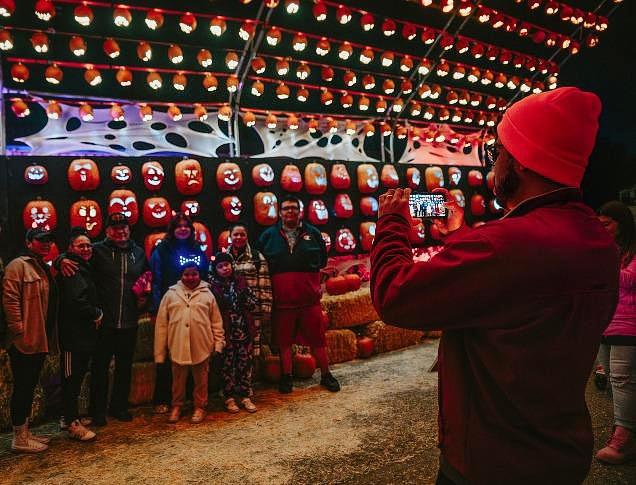 A woman with various children surrounding her near a fall display with hay and pumpkins at Clovermead Adventure Farm