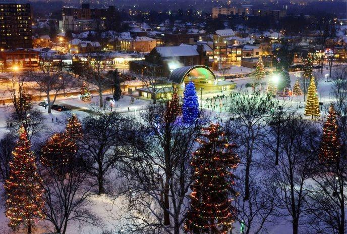 Victoria park glows with Christmas lights and a festive crowd around a lit-up pavilion at night.