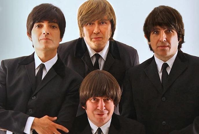 Four group members posing as the Beatles for a photo.