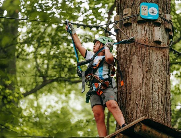 A kid climbs a rope bridge in the trees at Boler Mountain's Treetop Adventure Park in London, Ontario.