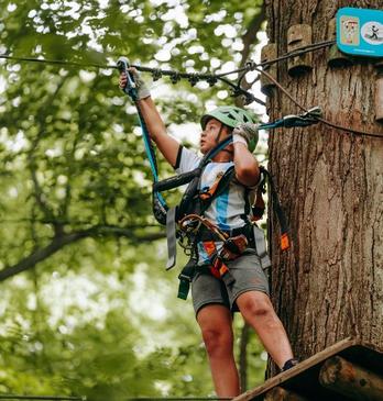 A kid climbs a rope bridge in the trees at Boler Mountain's Treetop Adventure Park in London, Ontario.