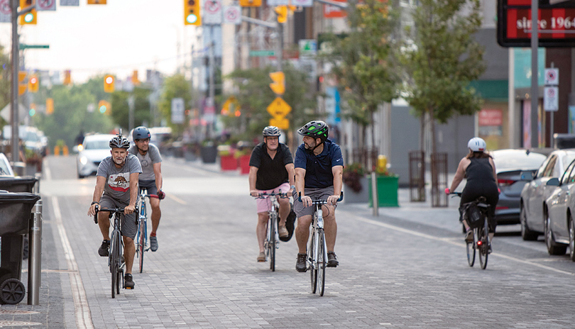 A group of males cycling on a stone brick road on Dundas Street in Downtown London, Ontario