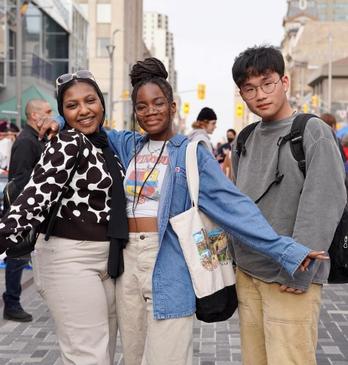 Three friends pose at an outdoor vintage market on Dundas Place.