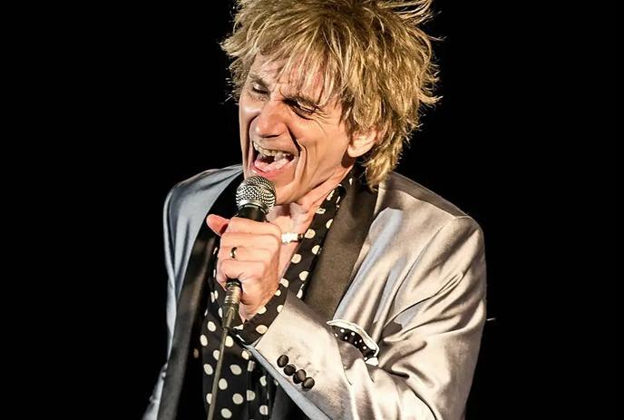 Doug Varty dressed as Rod Stewart performing on stage.