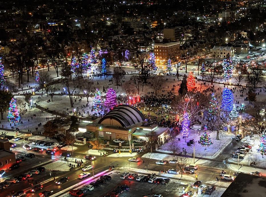 An aerial view of  Victoria Park in the evening with several trees are lit with colourful lights located in London, Ontario
