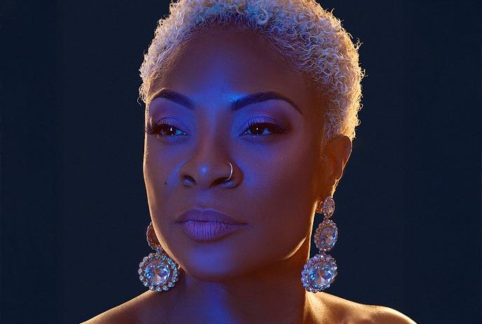 A headshot of Jully Black, posing for the camera in front of a blue background.