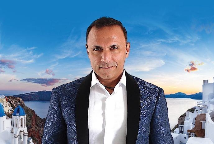 Pavlo standing in front of a beautiful Greek town with water in the distance.