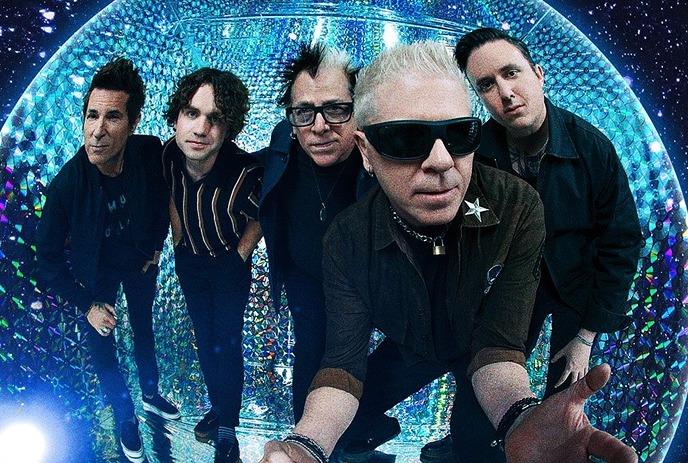 The band The Offspring posing dynamically inside a glowing disco ball set against a starry space backdrop.