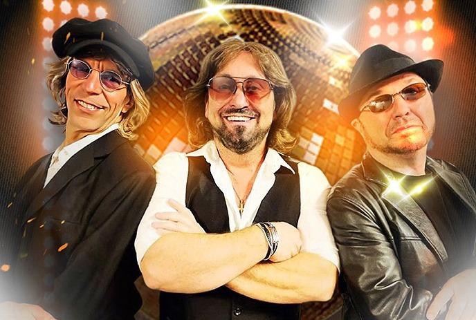 Three band members wearing sunglasses, posing in front of a disco ball.