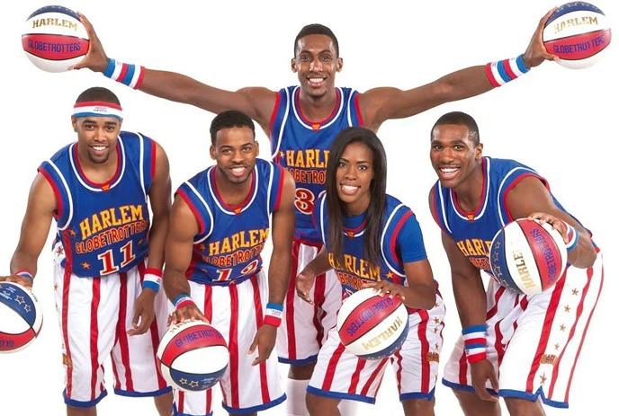 Five team members with basketballs pose for a photo in their team uniforms.