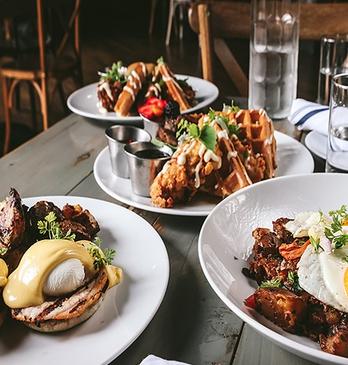 three plates of brunch inspired food on a grey wooden table