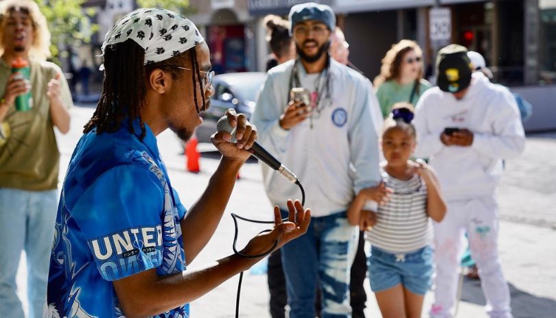 A singer performing in front of people at Dundas Place.