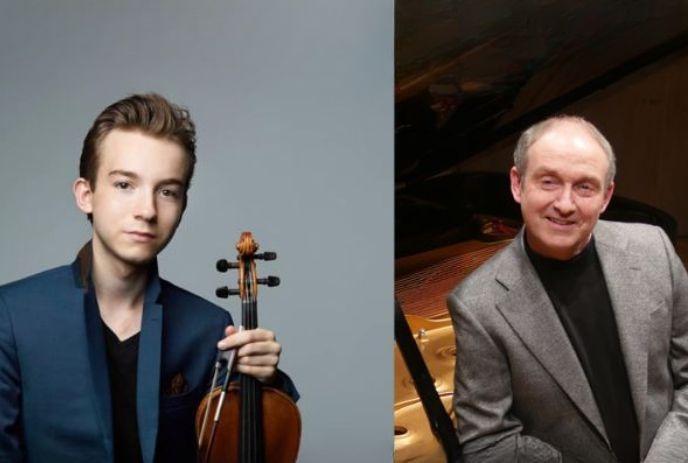 Musicians in suites, near a piano, one holding a violin, posing for the picture.