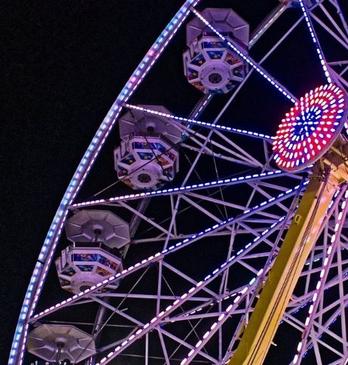 A night shot of the Western Fair with rides and attractions lighting up the night sky.