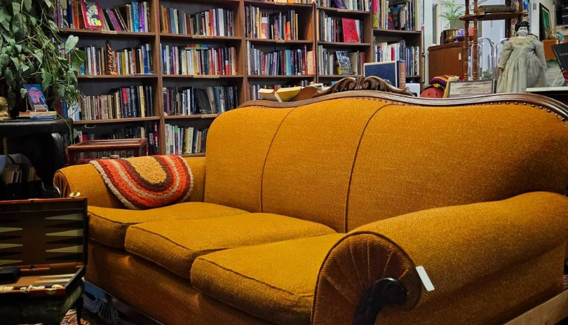 A yellow-orange vintage couch in a bookstore.