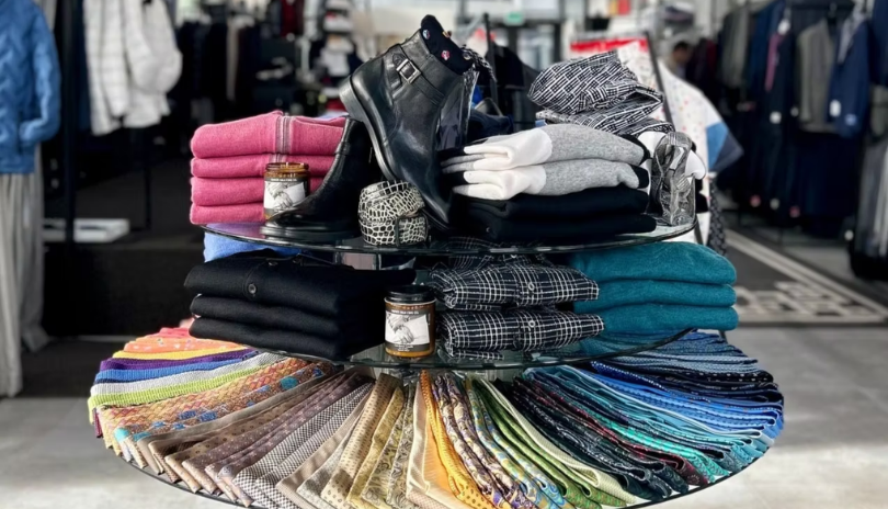 A circular store display with ties, shirts and shoes on it.
