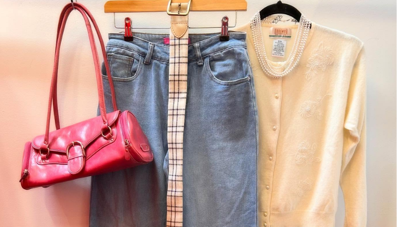 Vintage purse, jeans, belt and sweater hanging up in a row.